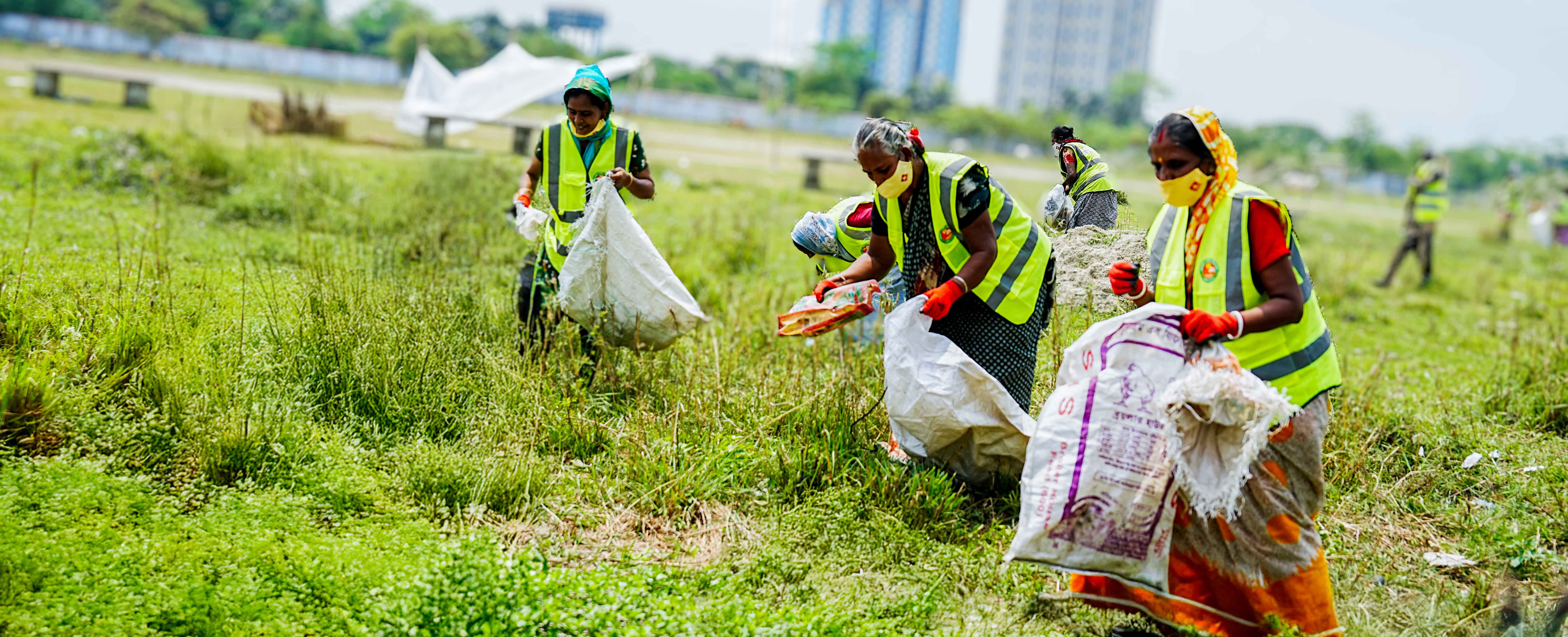 Waste collectors clean a field during a PRISTINE project cleanup campaign in Mongla